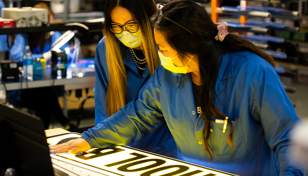 Production staff inspecting the Illuminated School Bus Sign